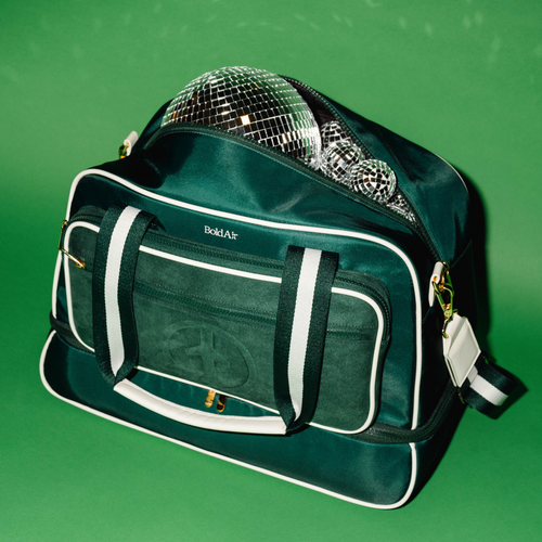 Front view of the green BoldAir Stayover Bag styled with silver disco balls, highlighting the women's weekender bag in an editorial scene.