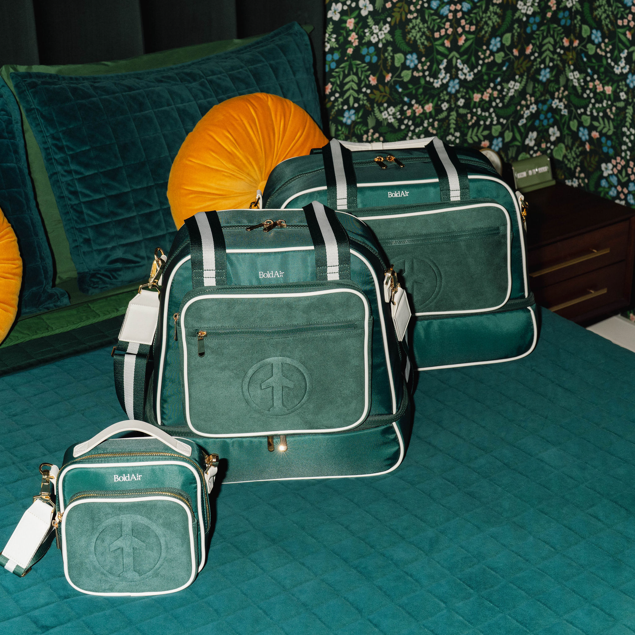 BoldAir Boarding Bag, Layover Bag, and Stayover Bag displayed on a hotel bed to compare the sizes of the three women's travel bags.